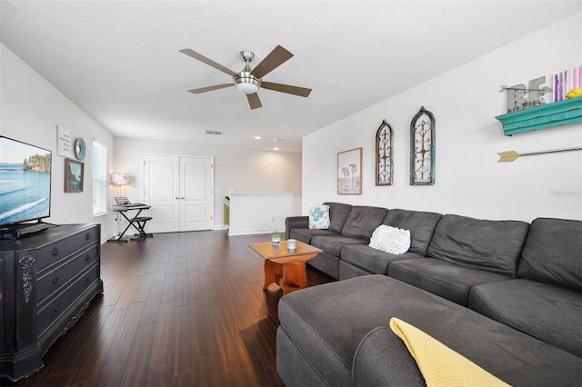 living room with a textured ceiling, ceiling fan, and dark hardwood / wood-style floors