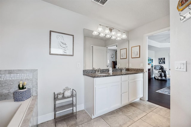 bathroom featuring a textured ceiling, a washtub, tile patterned flooring, and vanity