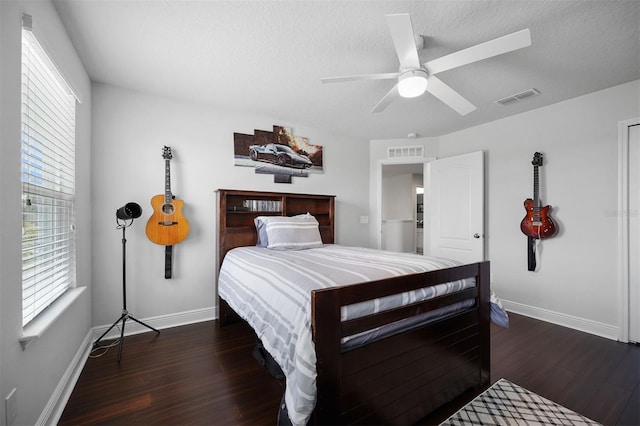 bedroom with a textured ceiling, ceiling fan, and dark wood-type flooring