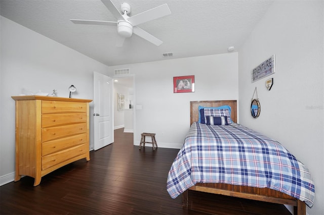 bedroom featuring dark wood-type flooring, a textured ceiling, and ceiling fan