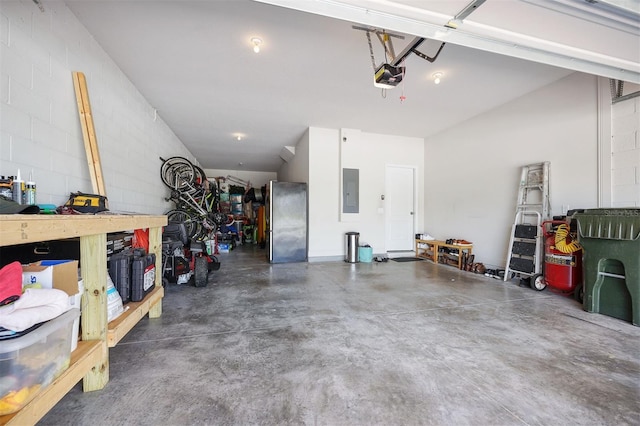 garage with a garage door opener, stainless steel refrigerator, electric panel, and a workshop area