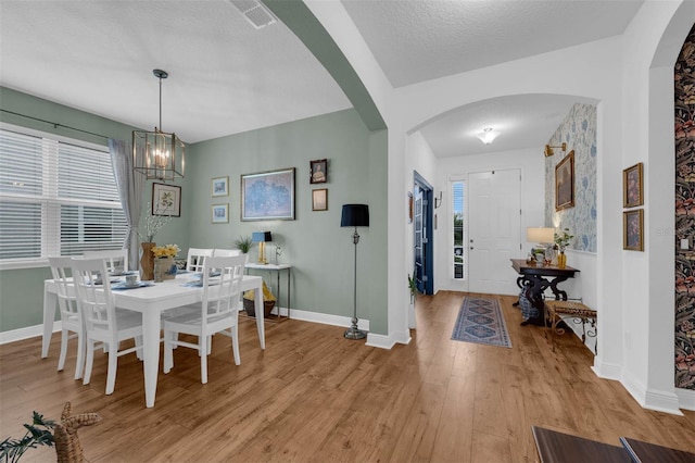 dining room with a textured ceiling, light hardwood / wood-style floors, and a chandelier