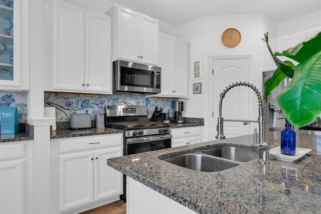 kitchen featuring appliances with stainless steel finishes, white cabinets, and dark stone countertops