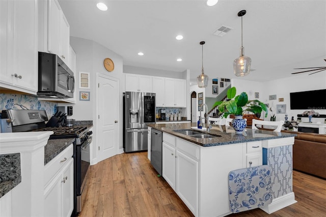 kitchen with a center island with sink, appliances with stainless steel finishes, white cabinetry, and sink