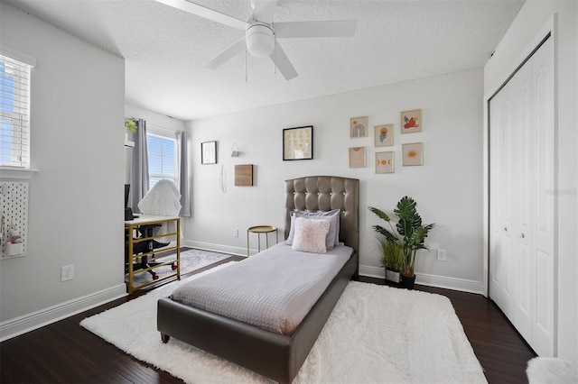 bedroom with dark wood-type flooring, a textured ceiling, ceiling fan, and a closet