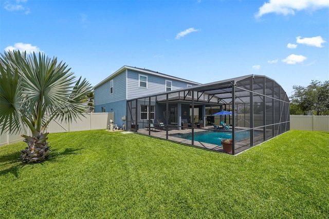 back of property with a patio area, glass enclosure, a yard, and a fenced in pool