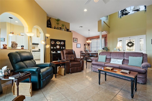 tiled living room with a towering ceiling and ceiling fan with notable chandelier