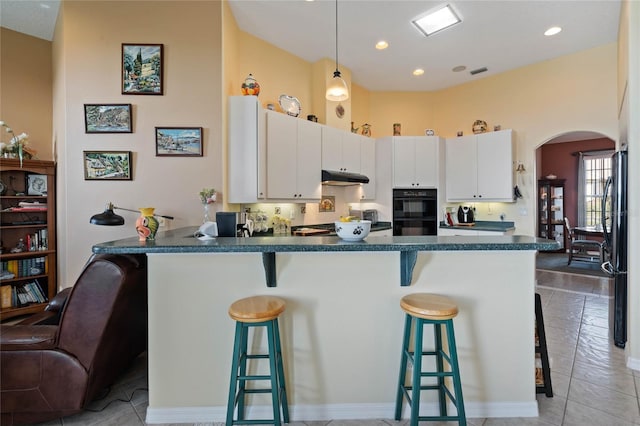 kitchen featuring pendant lighting, a kitchen breakfast bar, white cabinetry, and black appliances