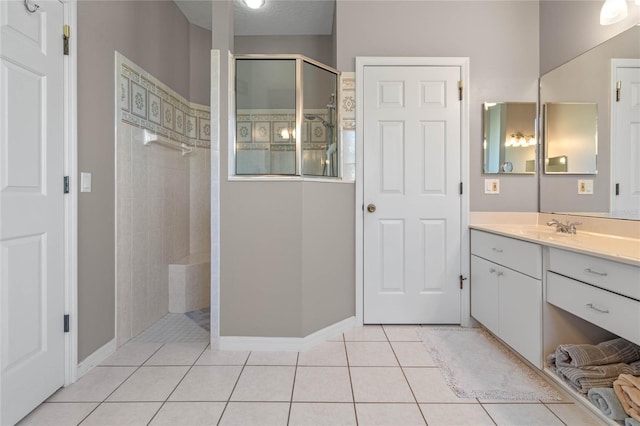 bathroom with tile patterned flooring, vanity, a tile shower, and a textured ceiling