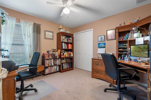 carpeted office space featuring a wealth of natural light, a textured ceiling, and ceiling fan