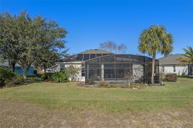 rear view of property featuring a lawn and a lanai