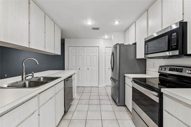 kitchen with white cabinets, light tile patterned flooring, sink, and stainless steel appliances