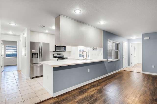 kitchen with white cabinets, plenty of natural light, sink, and appliances with stainless steel finishes