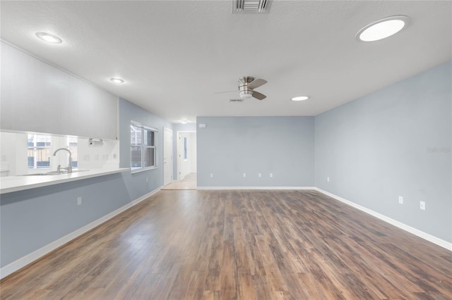 unfurnished living room with ceiling fan, sink, a textured ceiling, and hardwood / wood-style flooring