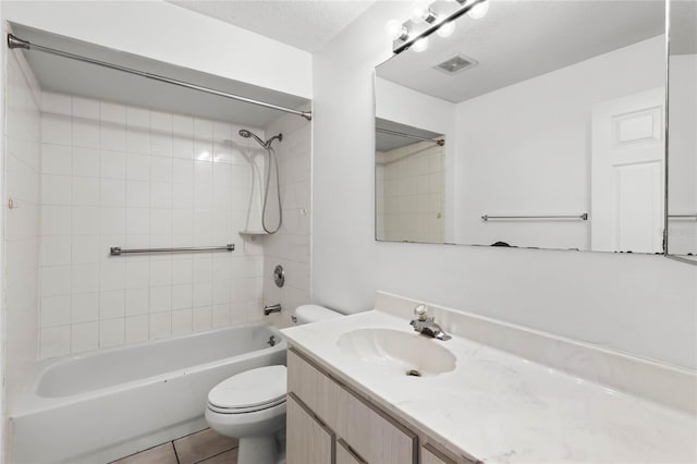 full bathroom featuring vanity, a textured ceiling, tile patterned flooring, toilet, and tiled shower / bath