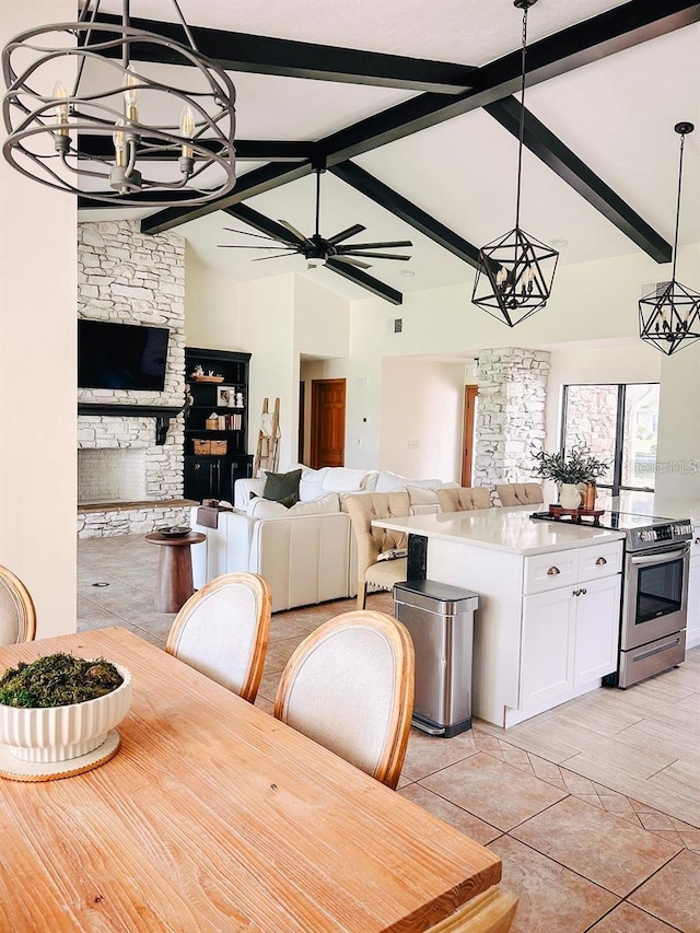 dining area with vaulted ceiling with beams, ceiling fan, and a stone fireplace