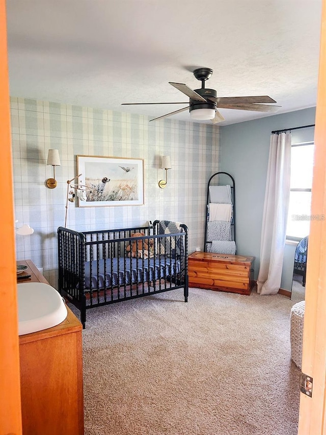 bedroom featuring a crib, carpet floors, and ceiling fan