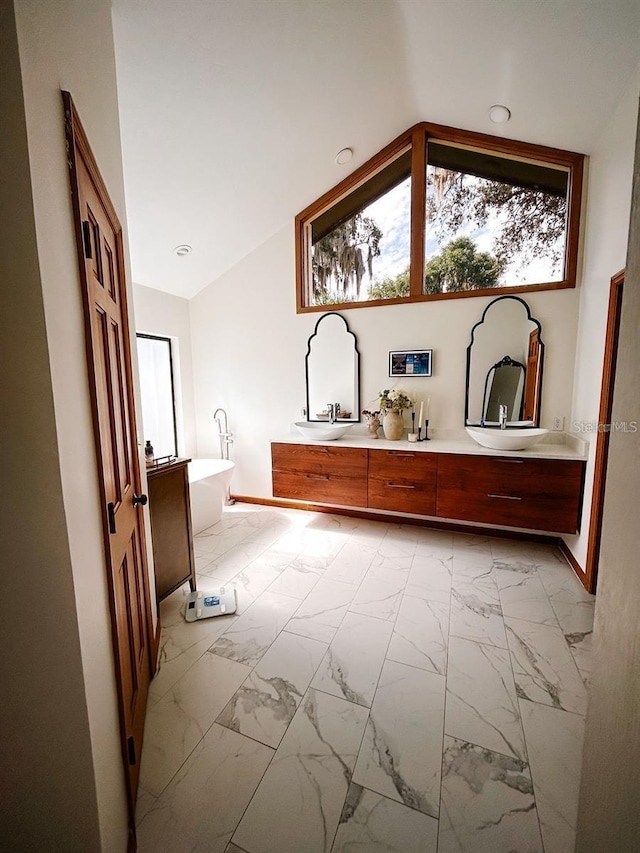 bathroom featuring vanity, a tub to relax in, and lofted ceiling