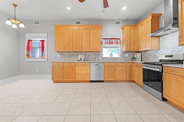 kitchen featuring decorative backsplash, appliances with stainless steel finishes, ceiling fan, wall chimney range hood, and light tile patterned floors