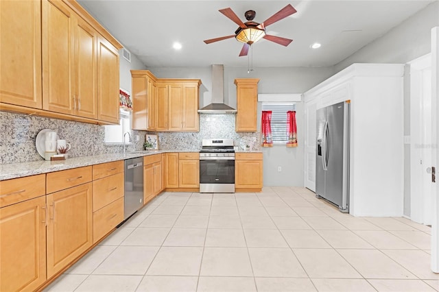 kitchen featuring backsplash, wall chimney range hood, sink, appliances with stainless steel finishes, and light stone counters