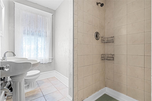 bathroom with toilet, a tile shower, and tile patterned floors