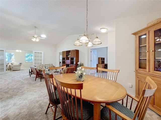 dining room featuring ceiling fan with notable chandelier, lofted ceiling, a textured ceiling, and light carpet