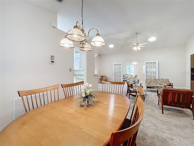 dining space featuring a textured ceiling, carpet, and ceiling fan with notable chandelier