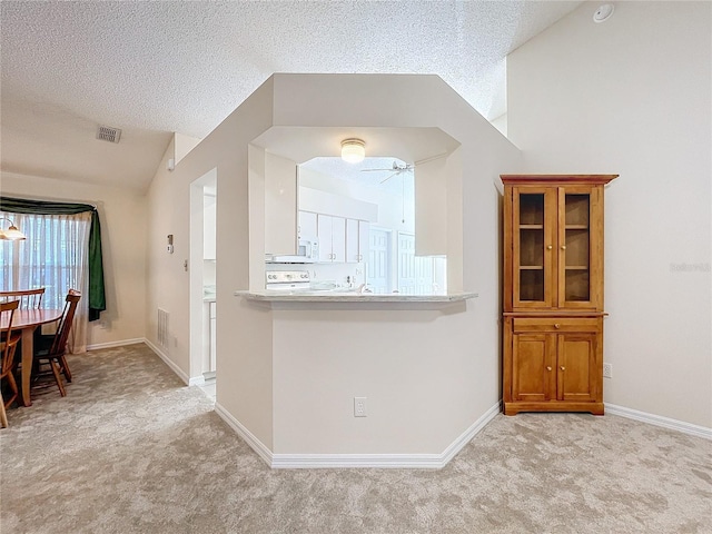 kitchen featuring ceiling fan, lofted ceiling, a textured ceiling, and light carpet