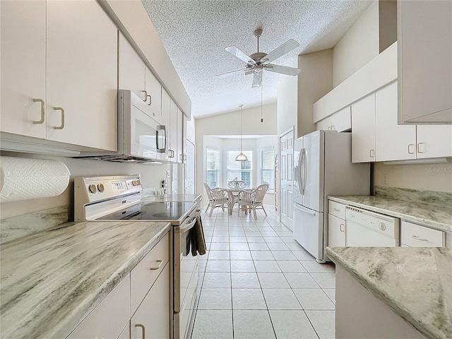 kitchen with a textured ceiling, white appliances, white cabinetry, and lofted ceiling