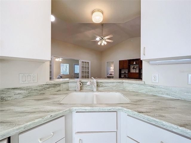 kitchen featuring white cabinets, sink, vaulted ceiling, ceiling fan, and light stone countertops