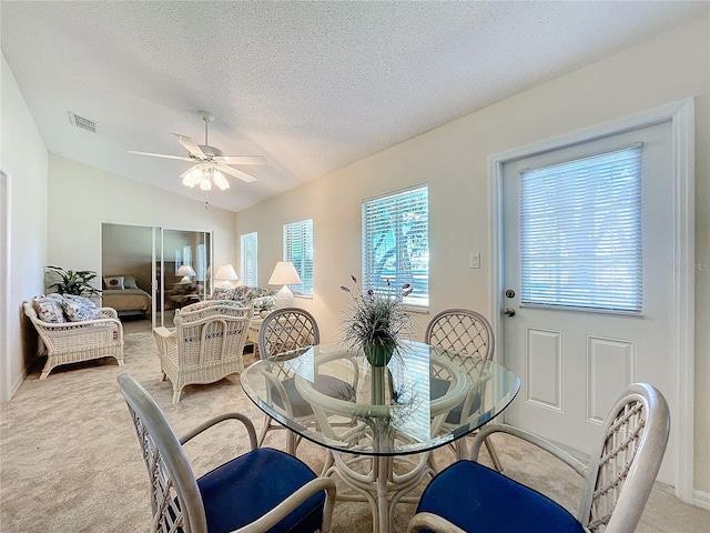 carpeted dining room with ceiling fan, a textured ceiling, and vaulted ceiling