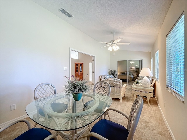 carpeted dining area with a textured ceiling, vaulted ceiling, and ceiling fan