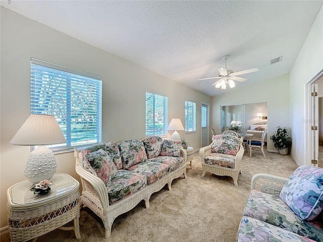 living room with light carpet, a textured ceiling, ceiling fan, and a healthy amount of sunlight