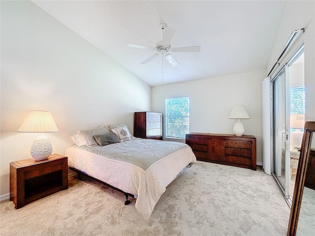 bedroom with ceiling fan, light colored carpet, lofted ceiling, and a textured ceiling