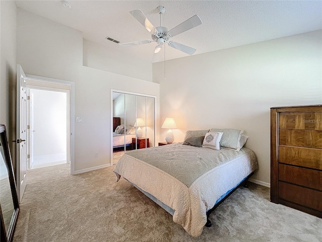 carpeted bedroom with ceiling fan, a closet, high vaulted ceiling, and a textured ceiling