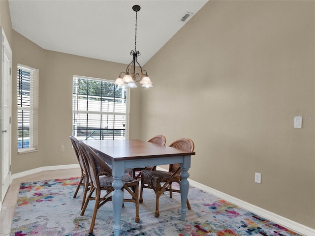 tiled dining room with an inviting chandelier and vaulted ceiling