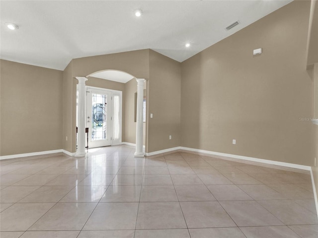 empty room with vaulted ceiling, decorative columns, and light tile patterned floors