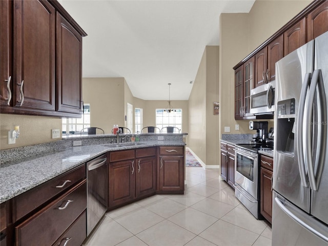 kitchen featuring light stone countertops, pendant lighting, light tile patterned floors, appliances with stainless steel finishes, and sink