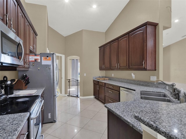 kitchen with sink, stainless steel appliances, light tile patterned flooring, and light stone counters