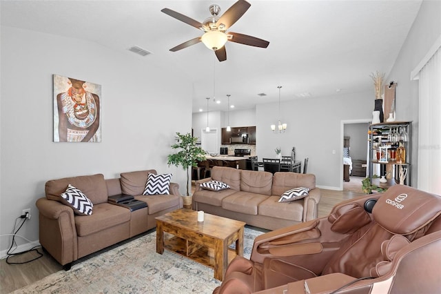 living room featuring ceiling fan with notable chandelier and light wood-type flooring