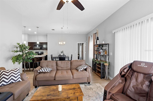 living room featuring ceiling fan with notable chandelier and light hardwood / wood-style floors