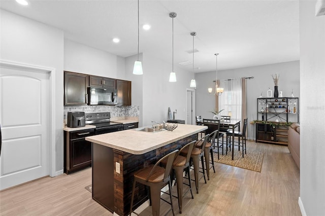 kitchen featuring pendant lighting, a kitchen island with sink, electric range, a kitchen bar, and dark brown cabinetry