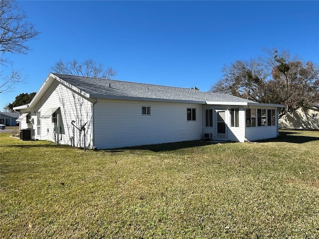 back of house featuring a lawn, a sunroom, and central air condition unit