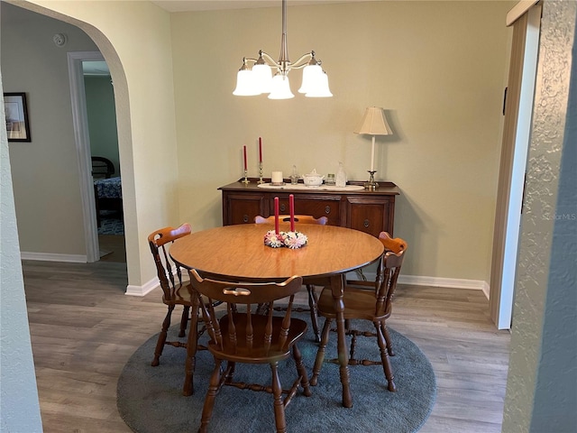 dining area with wood-type flooring and a notable chandelier