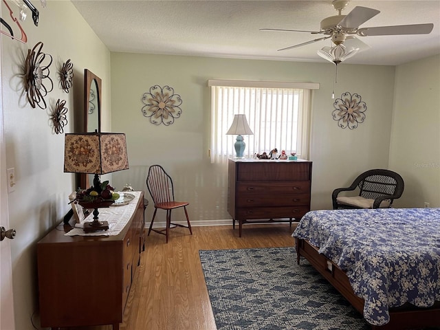 bedroom featuring ceiling fan, hardwood / wood-style floors, and a textured ceiling