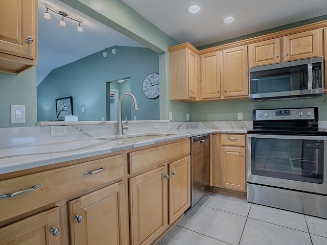 kitchen featuring vaulted ceiling, kitchen peninsula, light tile patterned flooring, sink, and appliances with stainless steel finishes