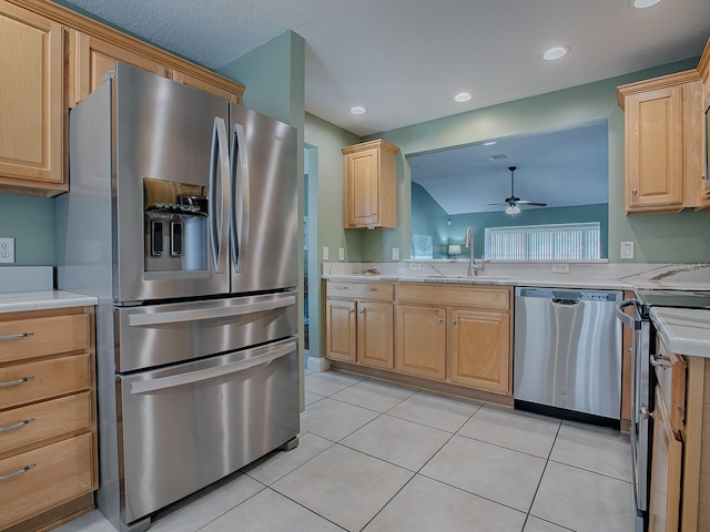 kitchen with appliances with stainless steel finishes, lofted ceiling, light brown cabinetry, sink, and light tile patterned flooring