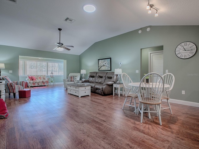 dining space with ceiling fan, hardwood / wood-style floors, and vaulted ceiling