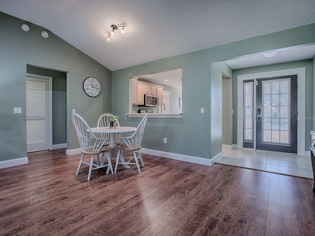 dining room with vaulted ceiling, a textured ceiling, and hardwood / wood-style flooring