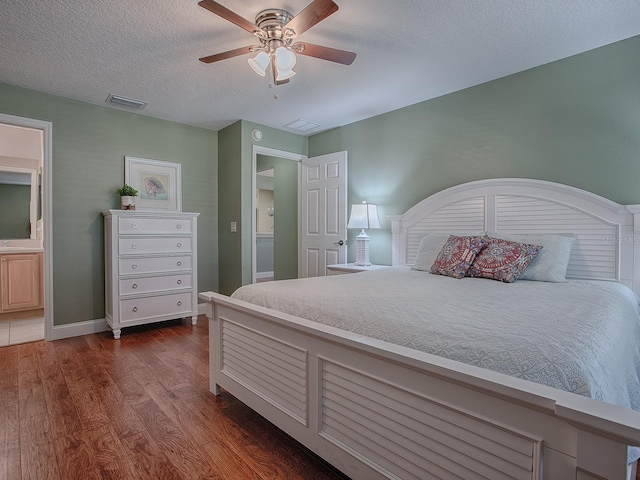 bedroom with dark wood-type flooring, ceiling fan, a textured ceiling, and ensuite bath